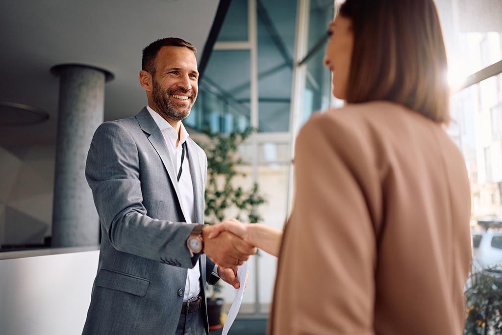 Mężczyzna i kobieta ściskają sobie dłonie, finalizując oficjalną umowę zakupu nieruchomości w Bułgarii.